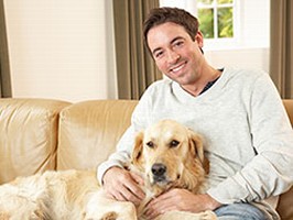 young man with golden retriever on sofa